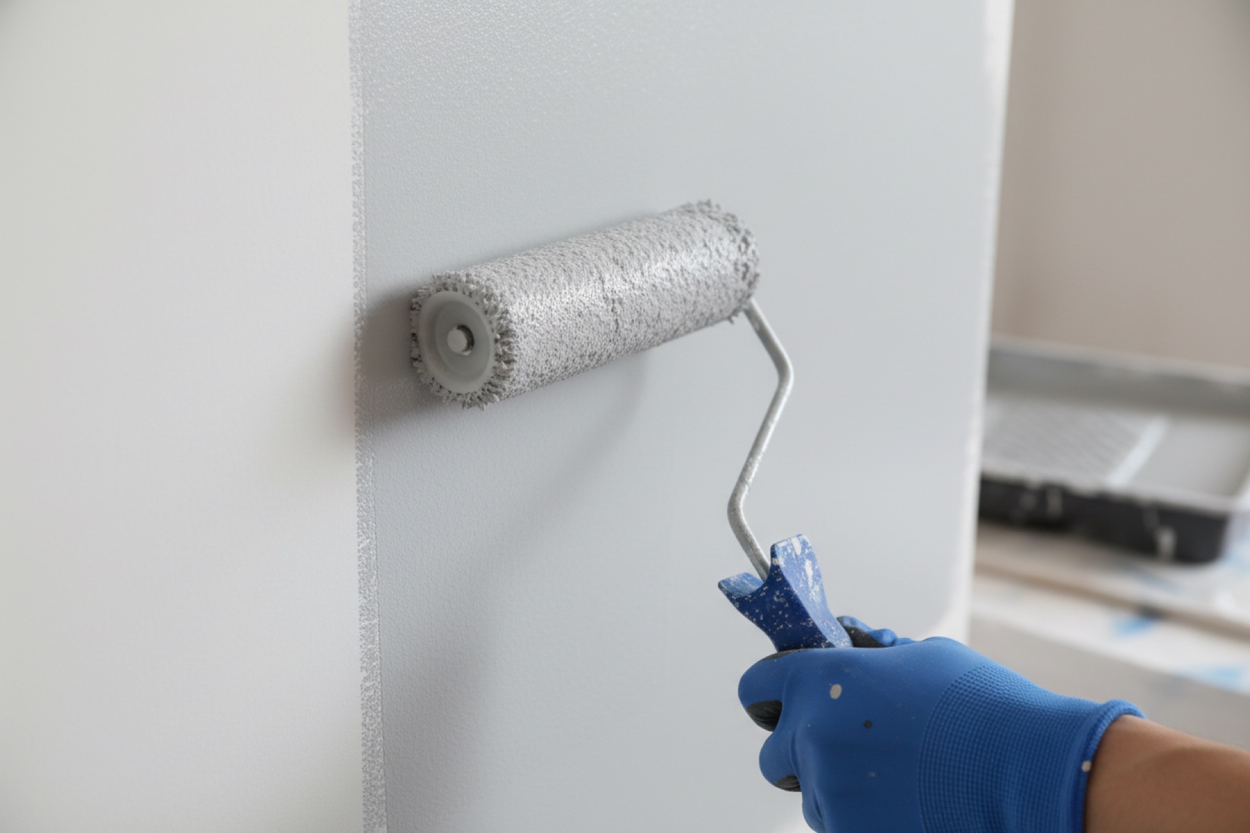 Professional painter rolling fresh paint on interior wall